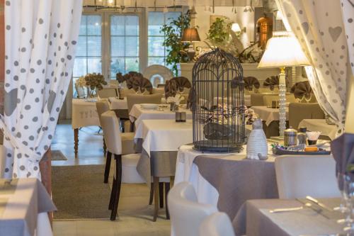 a restaurant with tables and chairs and a bird cage at LogisHotels Le Relais du Quercy in Meyssac