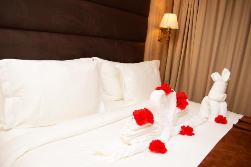 a bed with white towels and red flowers on it at Monty Suites & Golf in Uyo