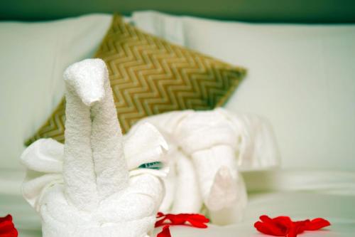 a pile of towels on a bed with red flowers at Monty Suites & Golf in Uyo