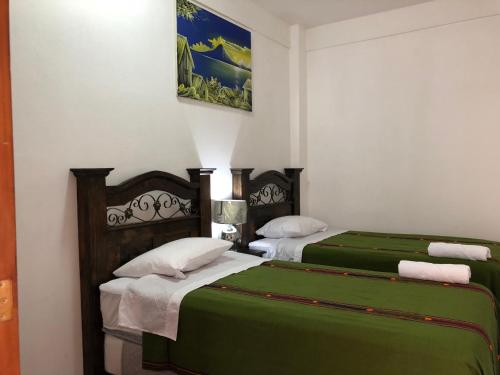 two beds in a room with green sheets at Hotel Los Angeles Panajachel in Panajachel