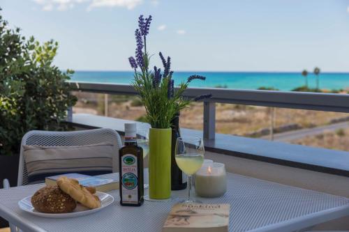 a table with a plate of food and a glass of wine at MareinSicilia: Talia Residence in Sampieri