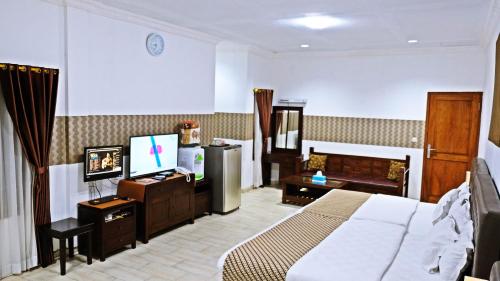 a bedroom with a bed and a desk and a television at BeOne House Jogja in Yogyakarta