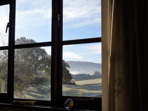 a window with a view of a field through it at Pwllgwilym B & B in Builth Wells