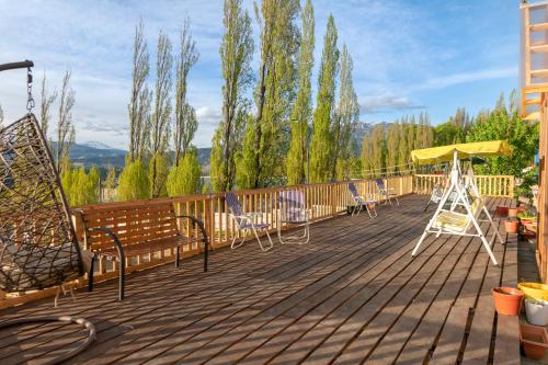 a deck with chairs and an umbrella and a swing at Hostal Los Teros in Coihaique