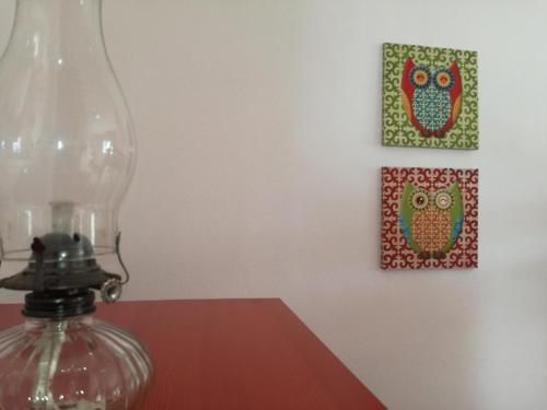 a glass lamp on a table with two pictures of owls at Pro Touristic Montejunto Villas in Arieiro