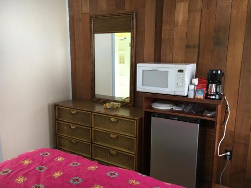 a bedroom with a microwave and a dresser with a bed at Holualoa bungalow 1 in Kailua-Kona