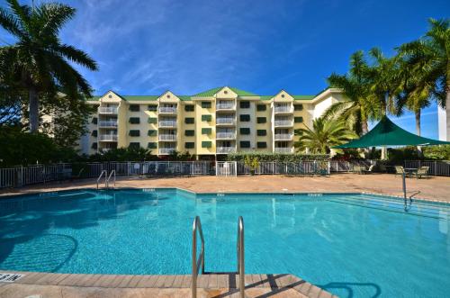 una piscina di fronte a un resort con palme di Sunrise Suites Tierra Bomba Suite #403 a Key West