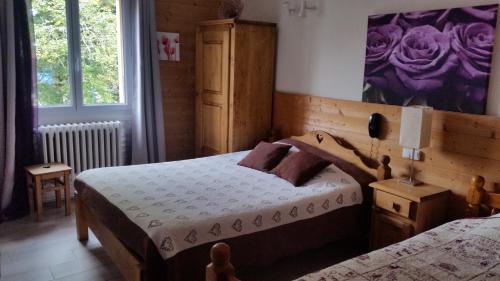 a bedroom with two beds and a painting on the wall at Hotel Restaurant LE YETI in Les Rousses