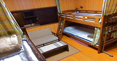 um quarto com três beliches e um sofá em 8Bed Dormitory Room - Aoshima Guesthouse Hooju - Vacation STAY 6198 em Miyazaki