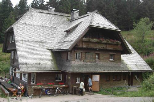 a large wooden house with people standing in front of it at WEITBLICK "entspannen - wohlfühlen - aktiv erholen" in Elzach