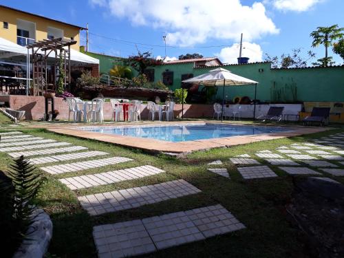 uma piscina num quintal com cadeiras e um guarda-sol em Pousada Guinda DIAMANTINA -MG em Diamantina