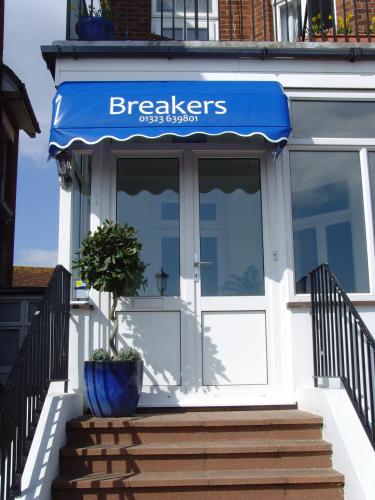 a front door of a bakery with a blue awning at Breakers Bed and Breakfast in Eastbourne