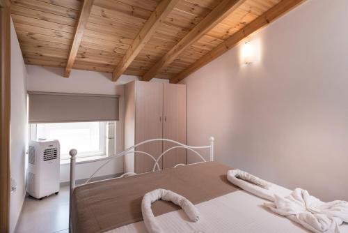 Cama blanca en habitación con techo de madera en Athina Apartments, en Plataniás