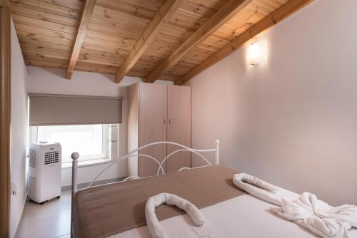 a white bed in a room with a wooden ceiling at Athina Apartments Near The Sea Platania in Plataniás