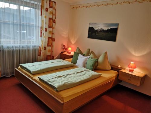 a bedroom with a bed and a window with two lamps at Vornbichlhof in Fieberbrunn