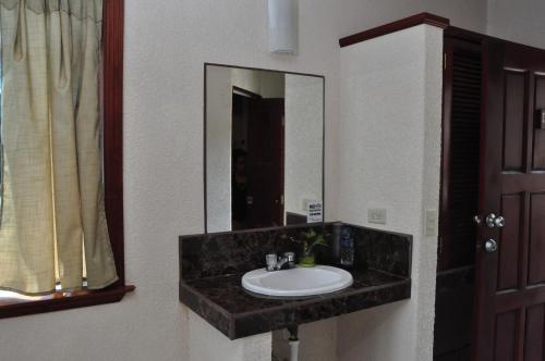 W łazience znajduje się umywalka i lustro. w obiekcie Lamanai Hotel & Marina w mieście Orange Walk