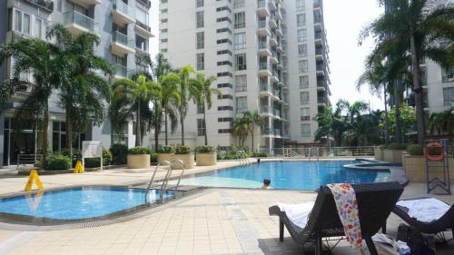 a swimming pool with chairs and palm trees and buildings at Palm Tree Condos across NAIA3 by Beth in Manila