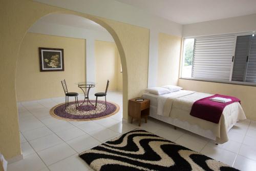 a bedroom with a bed and a table and chairs at Hotel Silveira in Bambuí