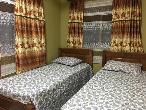 two twin beds in a room with curtains at Nabixx Residence in Brufut