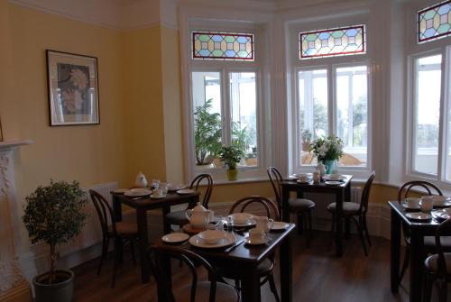 a dining room with tables and chairs and windows at Breakers Bed and Breakfast in Eastbourne