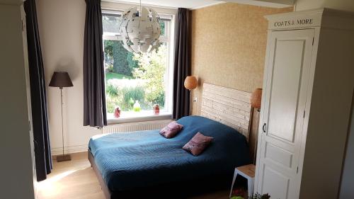 a bedroom with a blue bed and a window at Gastenverblijf Tjoene in Diepenveen