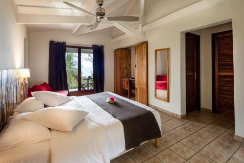 a bedroom with a white bed with a flower on it at Le Rayon Vert - Hôtel & Restaurant VUE SUR MER in Deshaies