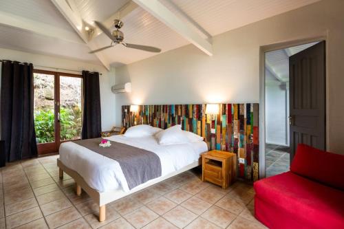 a bedroom with a white bed and a red couch at Le Rayon Vert Hôtel & Restaurant - Vue Mer in Deshaies