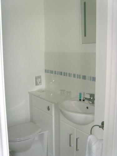 a white bathroom with a toilet and a sink at Breakers Bed and Breakfast in Eastbourne