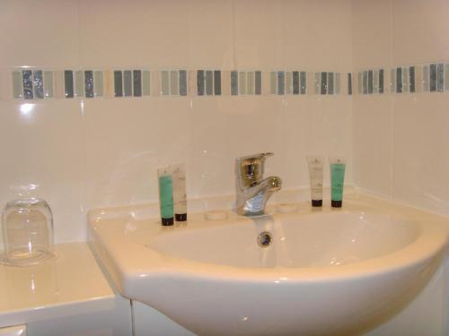 a white bathroom sink with two toothbrushes on it at Breakers Bed and Breakfast in Eastbourne