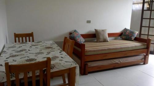 a bedroom with a bed and a table and chairs at Chalés Flamboyant in Caraguatatuba