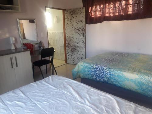 a bedroom with a bed and a desk and a mirror at BBN Guest House in Phuthaditjhaba