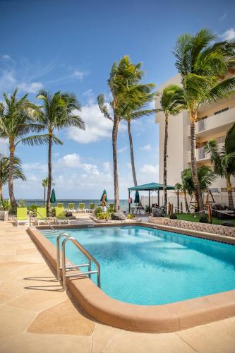 a swimming pool with palm trees in front of a building at Windjammer Resort and Beach Club in Fort Lauderdale