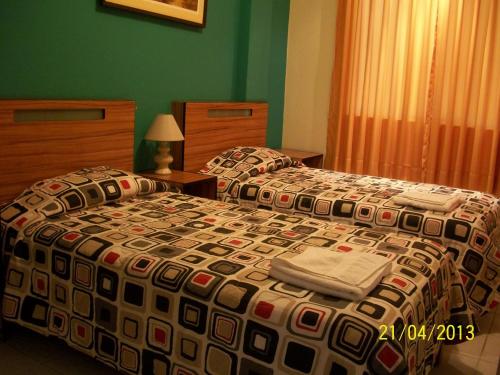 two beds in a hotel room with green walls at Hostal Hellen Ross in Nazca