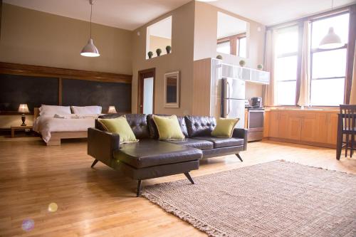 a living room with a leather couch and a bed at School 31 Lofts in Rochester