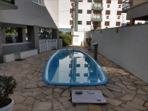 ein blauer Pool in einem Innenhof mit einem Gebäude in der Unterkunft Ap. Completo Enseada in Guarujá