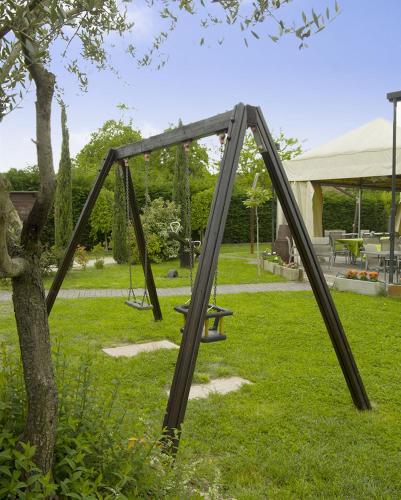 a wooden swing set in the grass next to a tree at SPIEDO IMPERIALE - Locanda e Ristorante in Cotignola