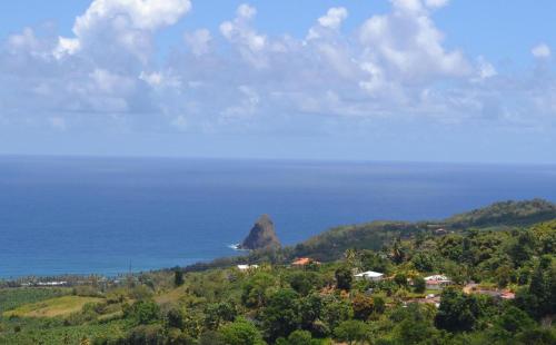 an island in the ocean with a rock in the distance at Haut de villa dans son écrin de verdure in Sainte-Marie