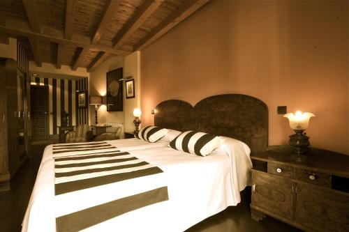 a bedroom with a large white bed with black and white pillows at Hotel-Hospedería los Templarios in Sepúlveda