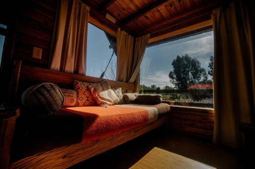 a bed in a room with a large window at Cabañas Valle de los Ciervos in Tandil