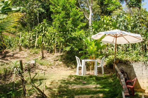 a table and an umbrella and two white chairs at Casa da Pipoca in Morro de São Paulo