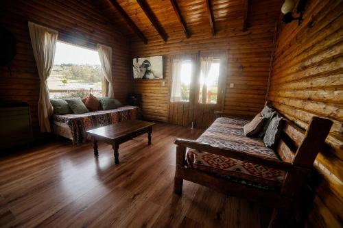 a living room of a log cabin with a couch and a table at Cabañas Valle de los Ciervos in Tandil