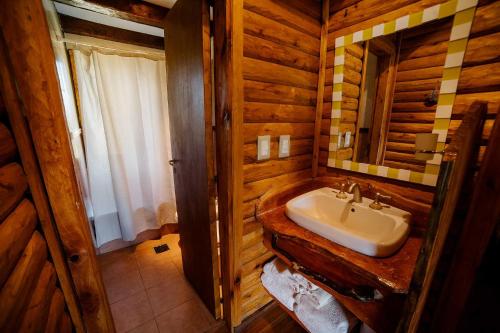a bathroom with a sink in a log cabin at Cabañas Valle de los Ciervos in Tandil