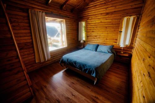a bedroom with a bed in a log cabin at Cabañas Valle de los Ciervos in Tandil