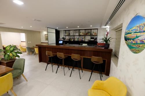 a lobby with a bar with stools and chairs at Tantur Hills Hotel - Jerusalem in Jerusalem