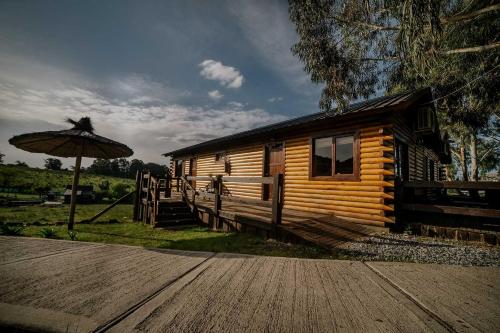 a cabin with an umbrella next to a wooden deck at Cabañas Valle de los Ciervos in Tandil
