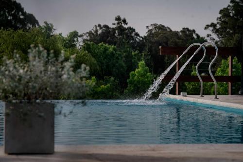a pool with a water fountain in the middle at Cabañas Valle de los Ciervos in Tandil