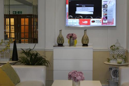 een woonkamer met een bank en een tv aan de muur bij Ababeel Hotel in Birmingham