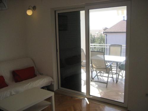 una puerta corredera de cristal que da a un balcón con mesa en Apartments Sonne, en Crikvenica