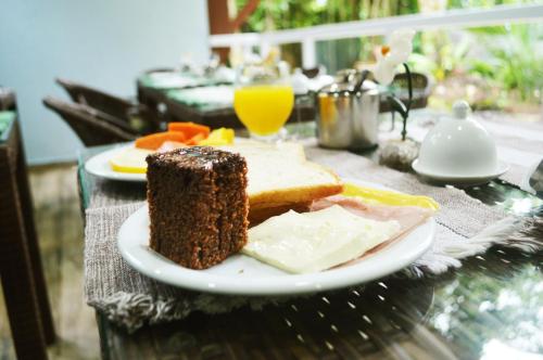 a plate of food with a piece of bread and orange juice at Pousada Guapuruvu in Abraão