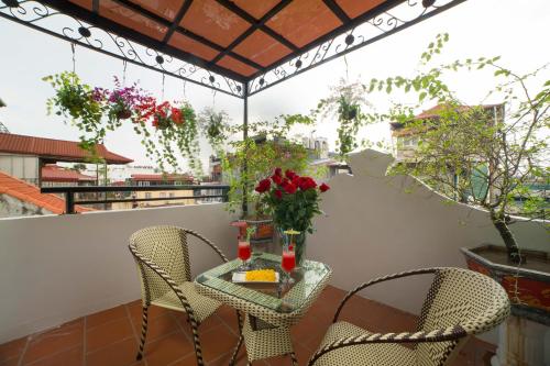 a table and chairs on a balcony with flowers at Golden Sail Hotel & Spa in Hanoi